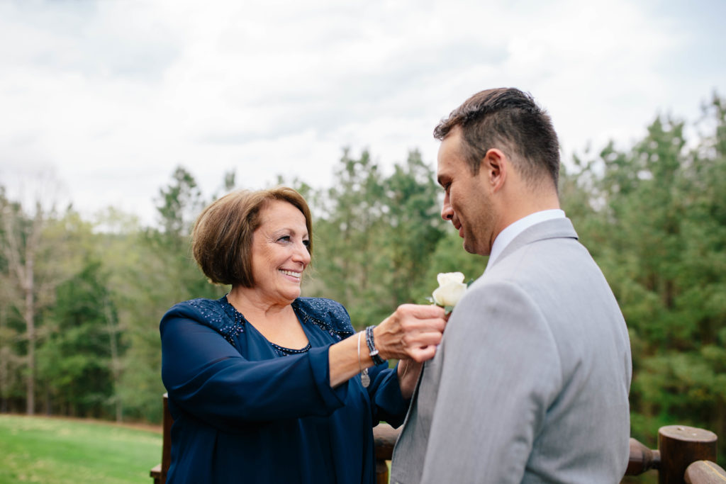 Mother of the groom putting on boutonnière 