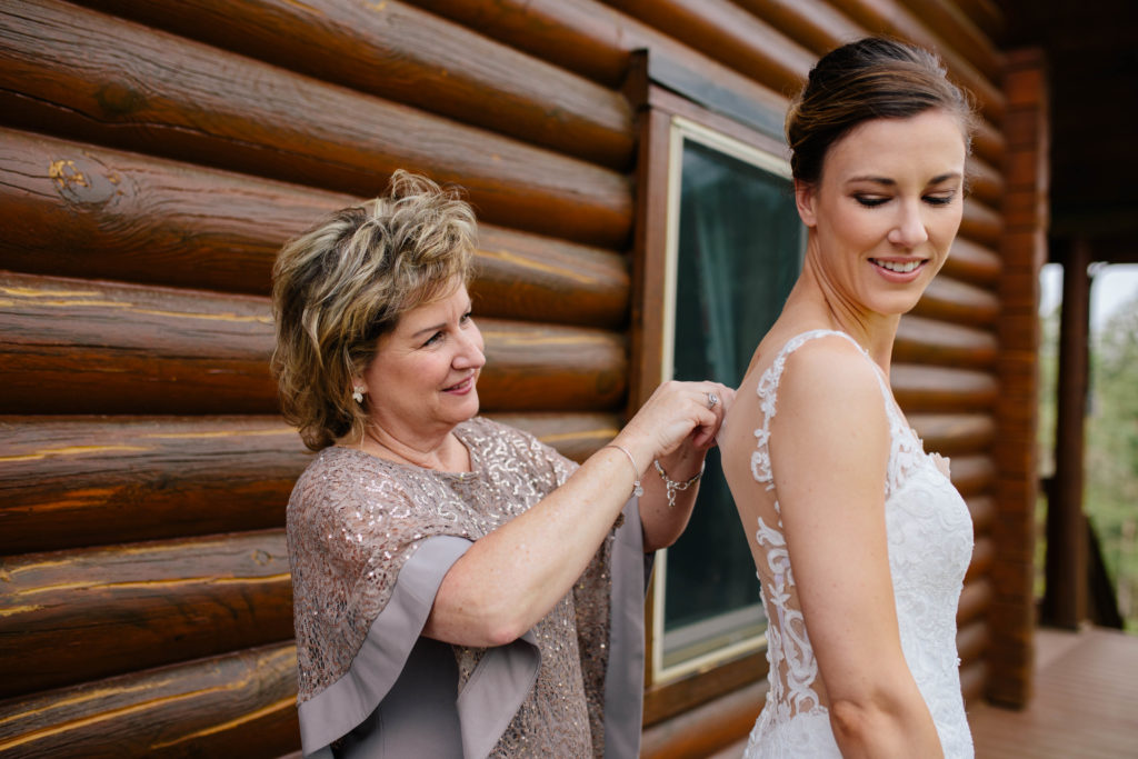 Mother of bride helping bride into dress
