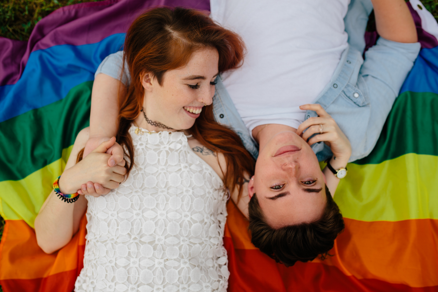 Two girls, in white shirts, laying on a colorful pride flag at Mill Creek Farm in North Carolina.