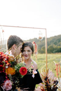 Bride and groom in front of gold ceremony arbor on top of a mountain at Mill Creek Farm in North Carolina.