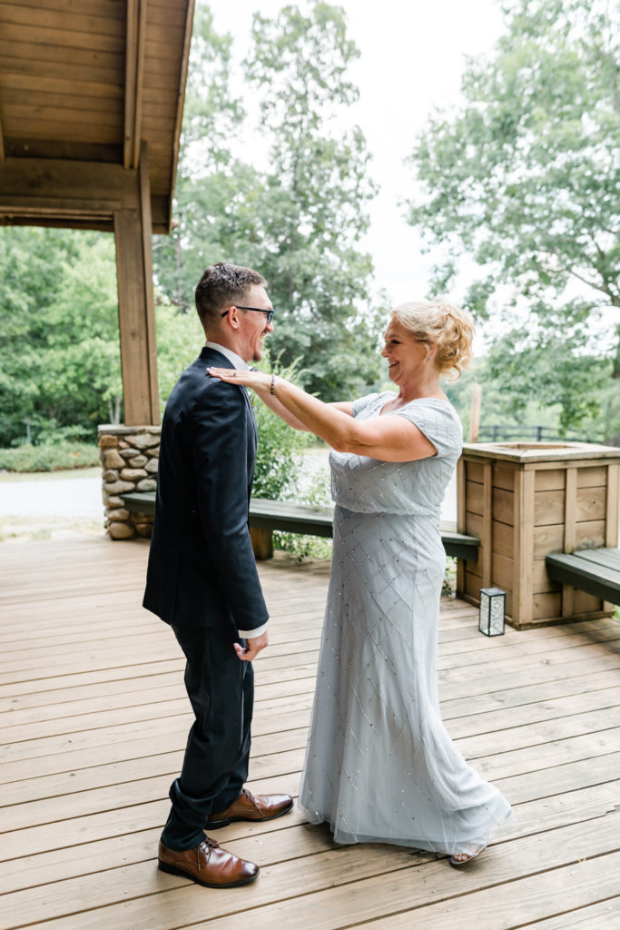 Groom, in navy suit, setting his mom for the first time at Carolina Country weddings venue in Charlotte.