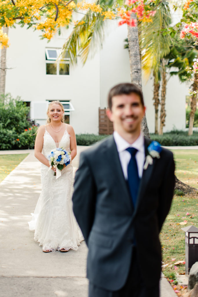 Bride, in white lace dress, seeing her groom, in a black suit, for the first time at the St. Lucia Grande Sandals Resort. Photographed by Charlotte wedding photographer.