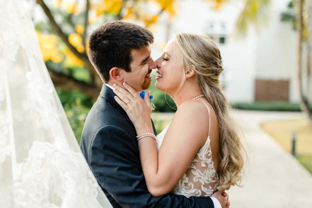 Bride, in white lace dress, almost kissing her groom, in a black suit, for the first time at the St. Lucia Grande Sandals Resort. Photographed by Charlotte wedding photographer.