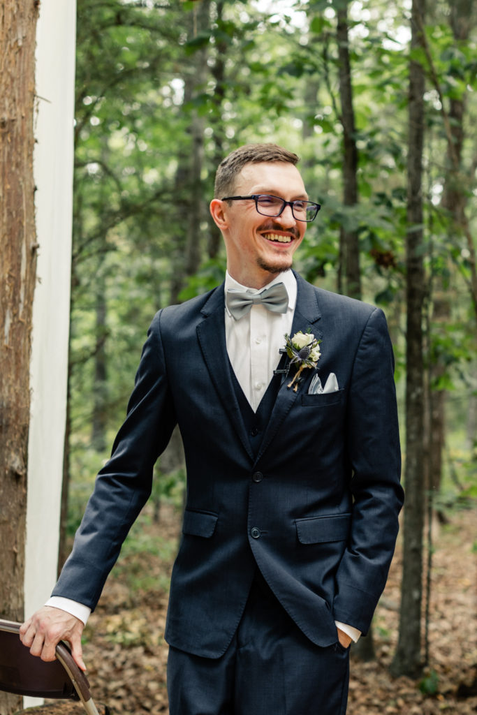 Groom, in navy suit, watching his bride walk down the aisle at Carolina Country weddings venue in Charlotte.