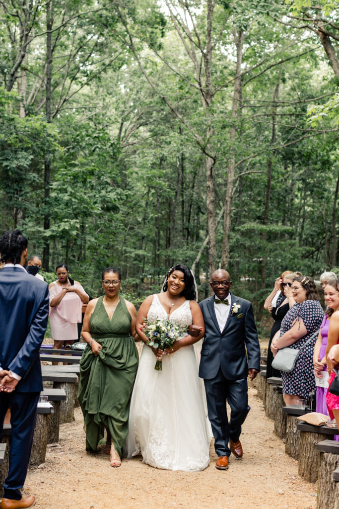 Bride, in white dress, walking down aisle with mom and dad at Carolina Country weddings venue in Charlotte.