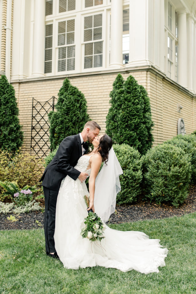 Bride in white dress kissing groom in blue suite at SePark Mansion Gastonia Wedding Venue. Photographed by Charlotte wedding photographer.