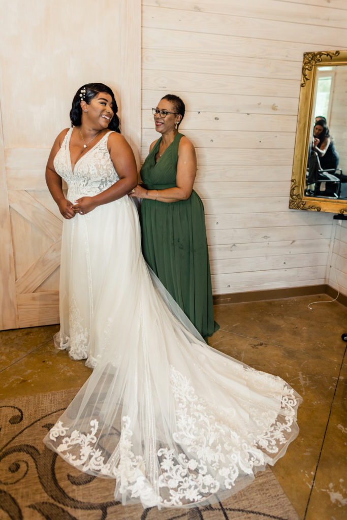 Bride getting into wedding dress with her mom at Carolina Country weddings venue in Charlotte.