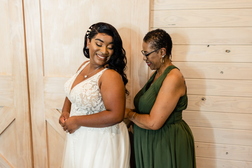 Bride getting into wedding dress with her mom at Carolina Country weddings venue in Charlotte.