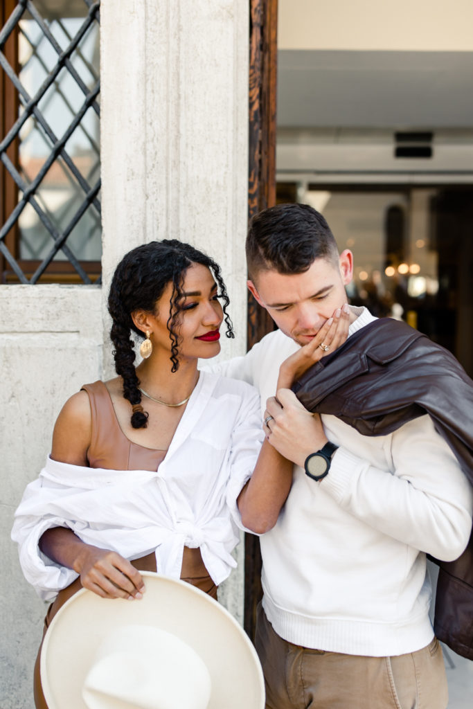 Girl, in brown leather dress and white button down, with boy, in white shirt and brown leather jacket, in Venice Italy. Photographed by Charlotte wedding photographer.
