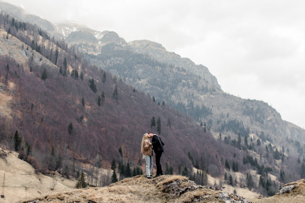 Boy and girl kissing on top of a mountain in Dolomites Italy. Photographed by Charlotte wedding photographer.