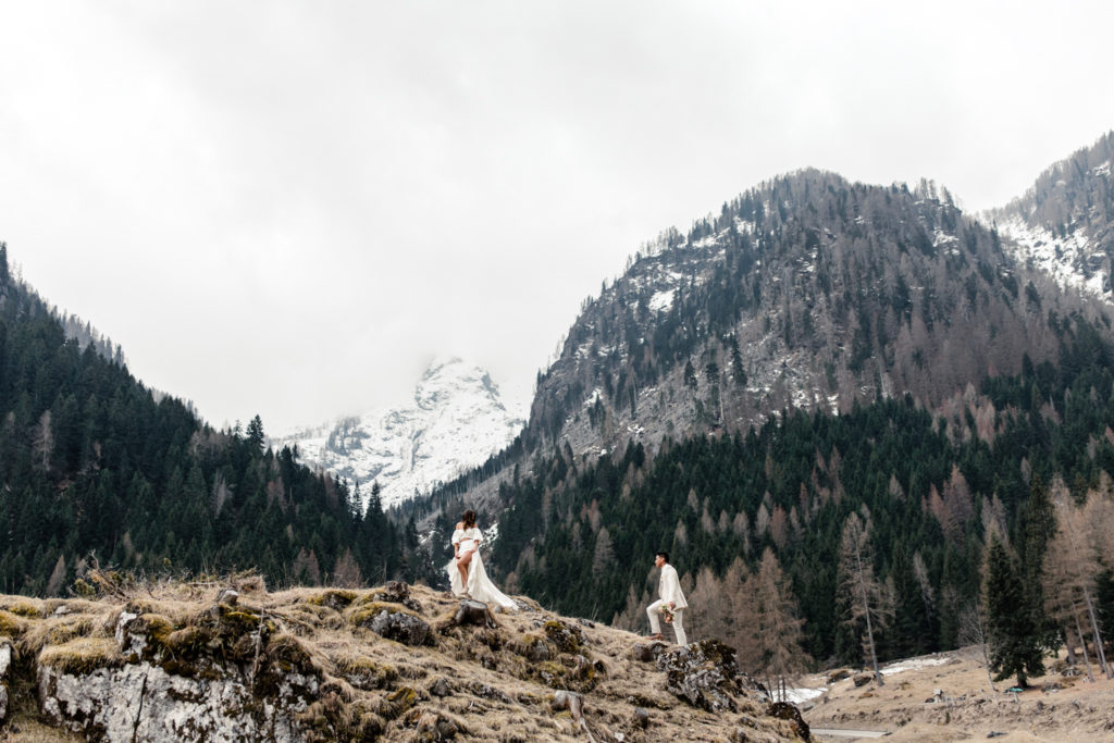 Bride, in white dress, walking up a mountain with groom, in cream suit, in Dolomites Italy. Photographed by Charlotte Wedding Photographer.