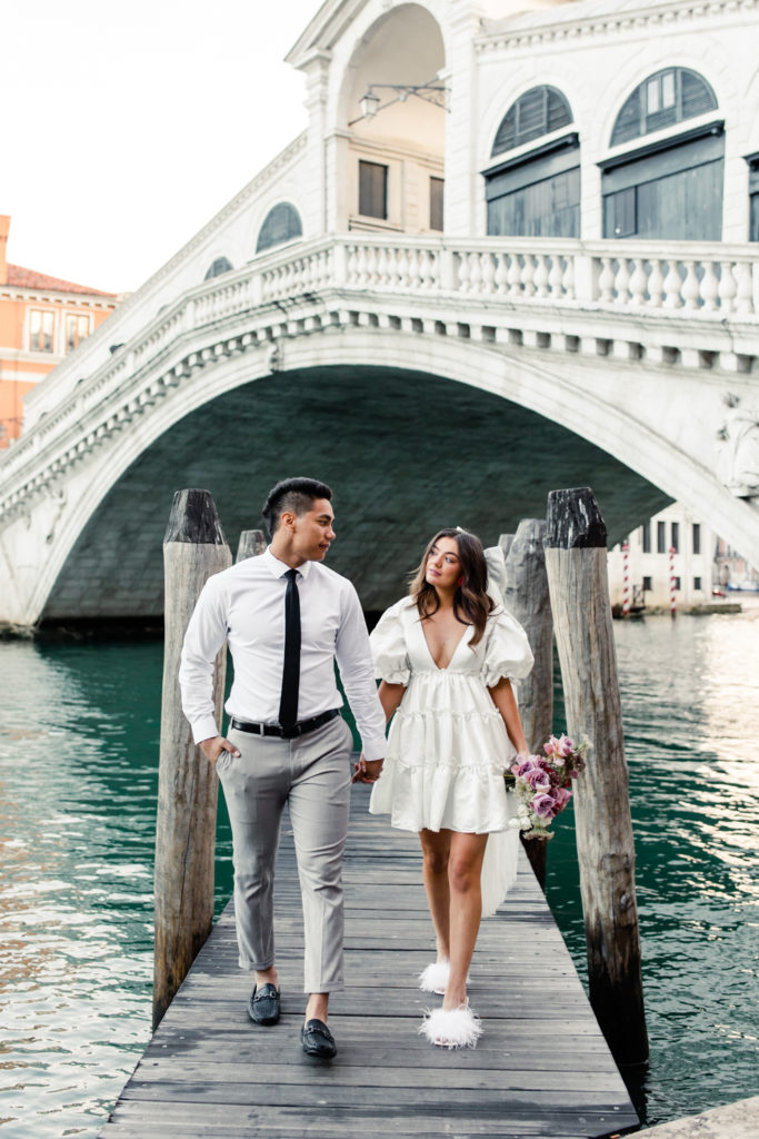 Bride, in white gown and veil, walking with groom in Venice Italy. Photographed by Charlotte wedding photographer. 