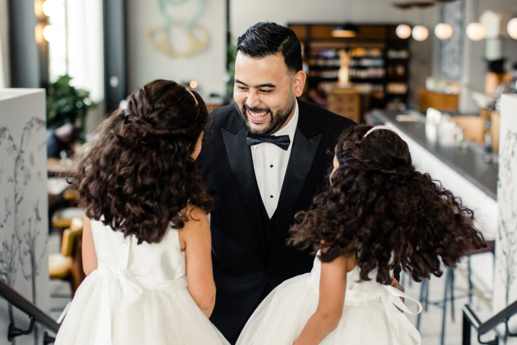 Groom, in black suit, seeing his two nieces, in white dresses, for the first time at The Highlawn Wedding venue in New Jersey. Photographed by Charlotte Wedding photographer.
