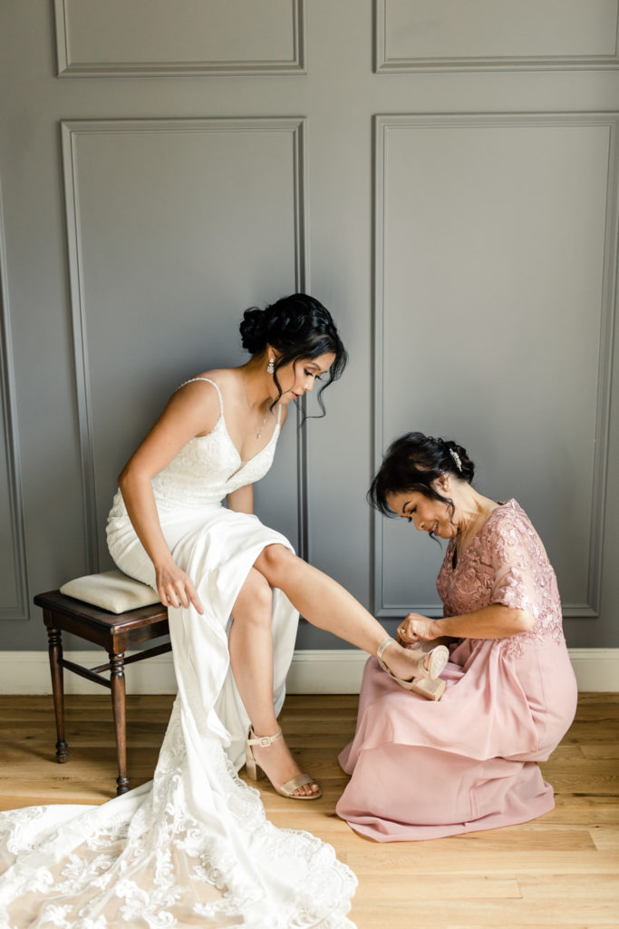 Bride getting in white lace dress with the help of her mom at the Bradford wedding venue in Raleigh NC.