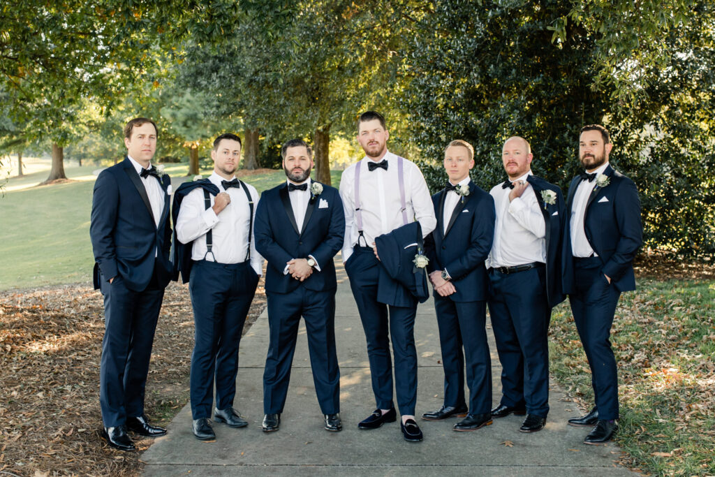 Groom and groomsmen dressed in navy suits and bowtie standing at Long View Country Club wedding venue in Charlotte NC