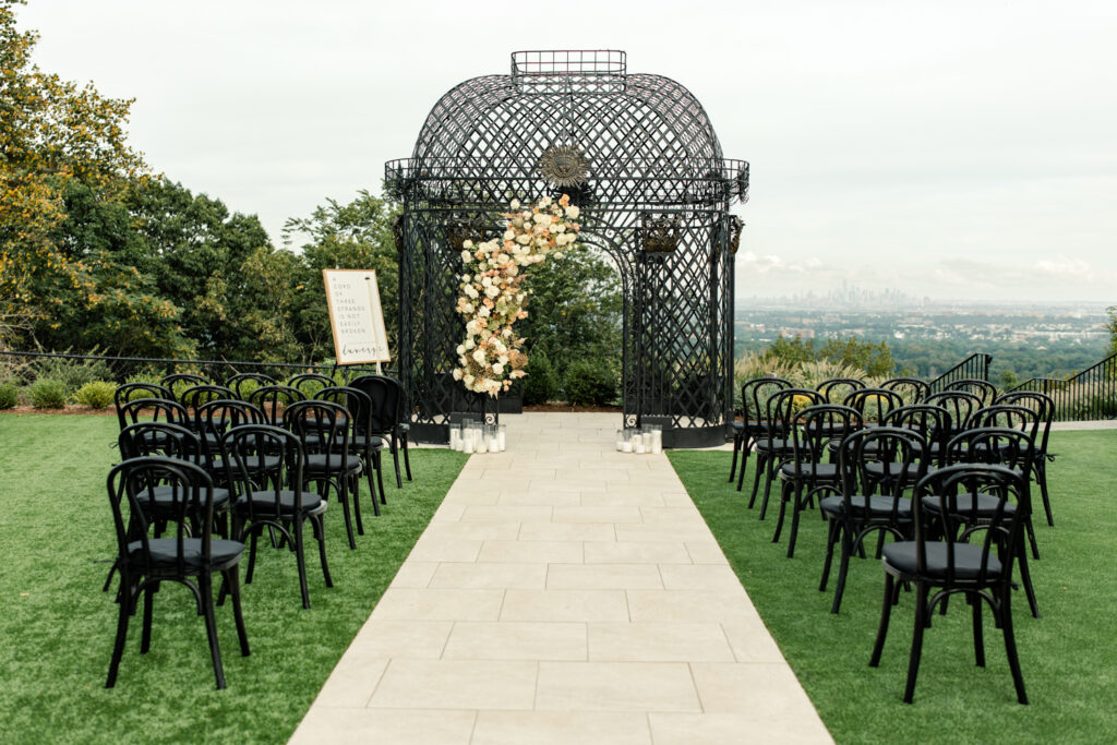 Wedding ceremony with black chairs and pink and white flowers at The Highlawn Wedding venue in New Jersey. Photographed by Charlotte Wedding photographer.