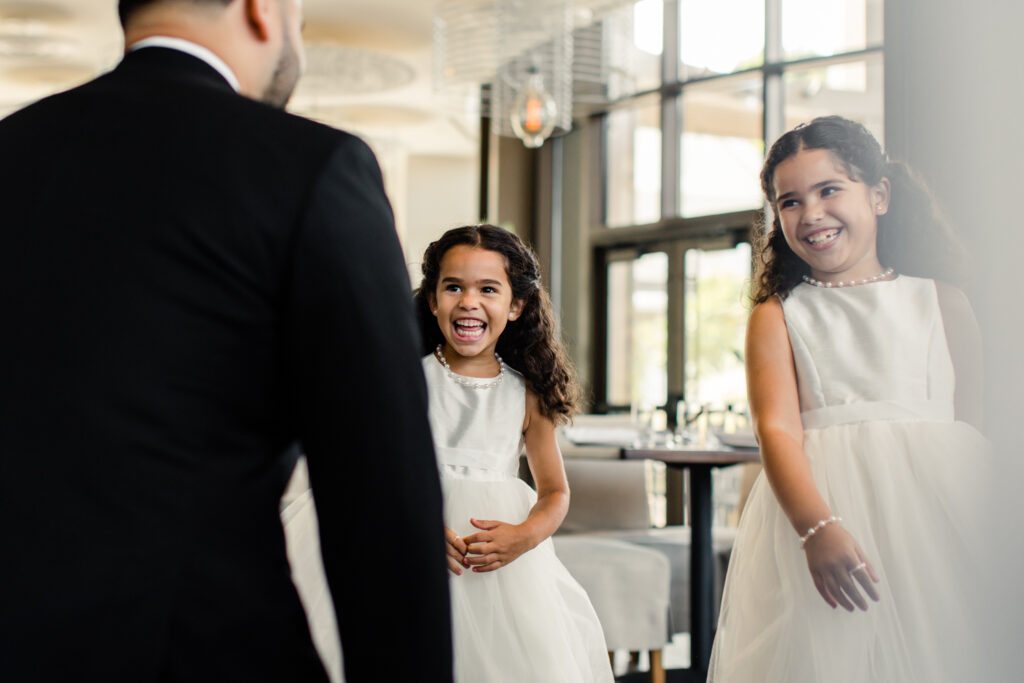 Groom, in black suit, seeing his two nieces, in white dresses, for the first time at The Highlawn Wedding venue in New Jersey. Photographed by Charlotte Wedding photographer.