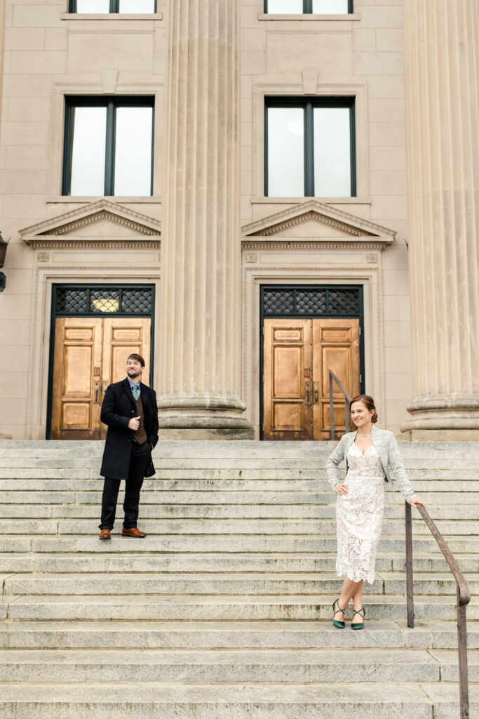 Bride and groom stand on opposite sides of a large staircase in uptown charlotte NC. Photographed by Stephanie Bailey Photography. 