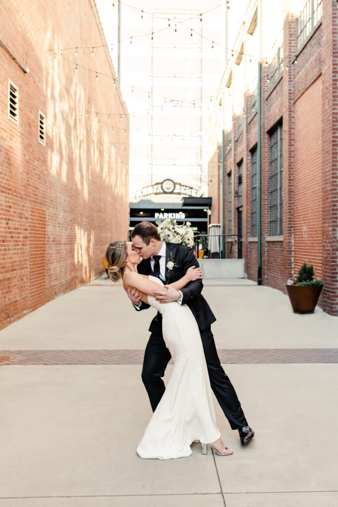 Bride in white dress kissing groom in black suit kisses at Byron's south end wedding venue. Photographed by Charlotte wedding photographer. 