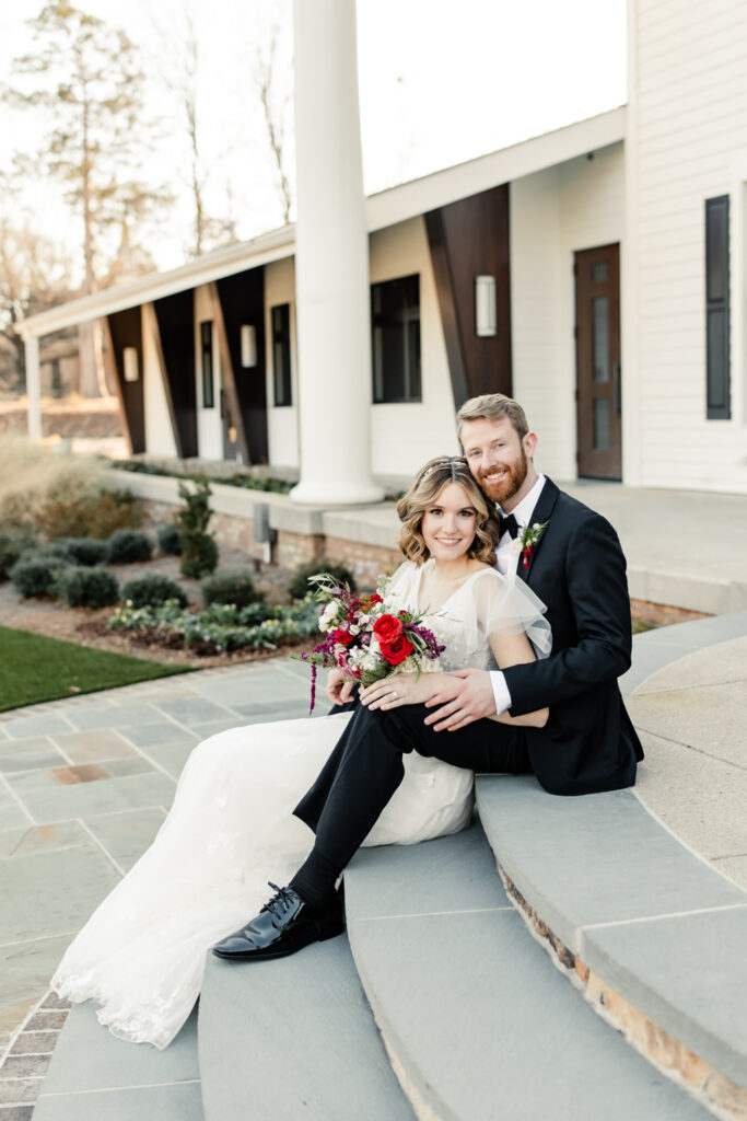 Bride, in white dress, sitting on stairs with groom, in black suit at 1705 East Raleigh Wedding Venue. Photographed by Charlotte Wedding Photographer, Stephanie Bailey Photography.