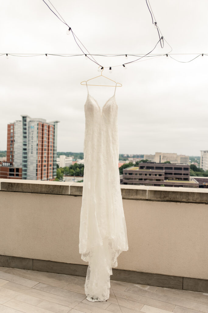 White laced wedding hanging from string of lights with uptown Charlotte in the background.