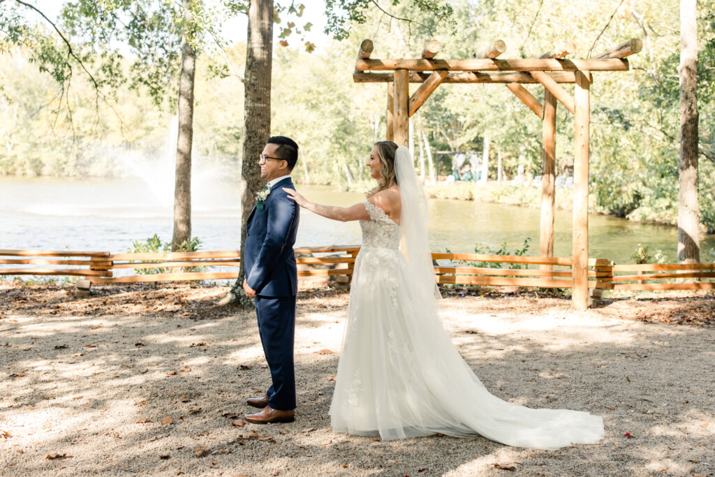 Bride with long blonde hair in a white lace dress seeing groom in blue suit for the first time at Riverwood Manor Wedding Venue. Photographed by Charlotte wedding photographer, Stephanie Bailey.