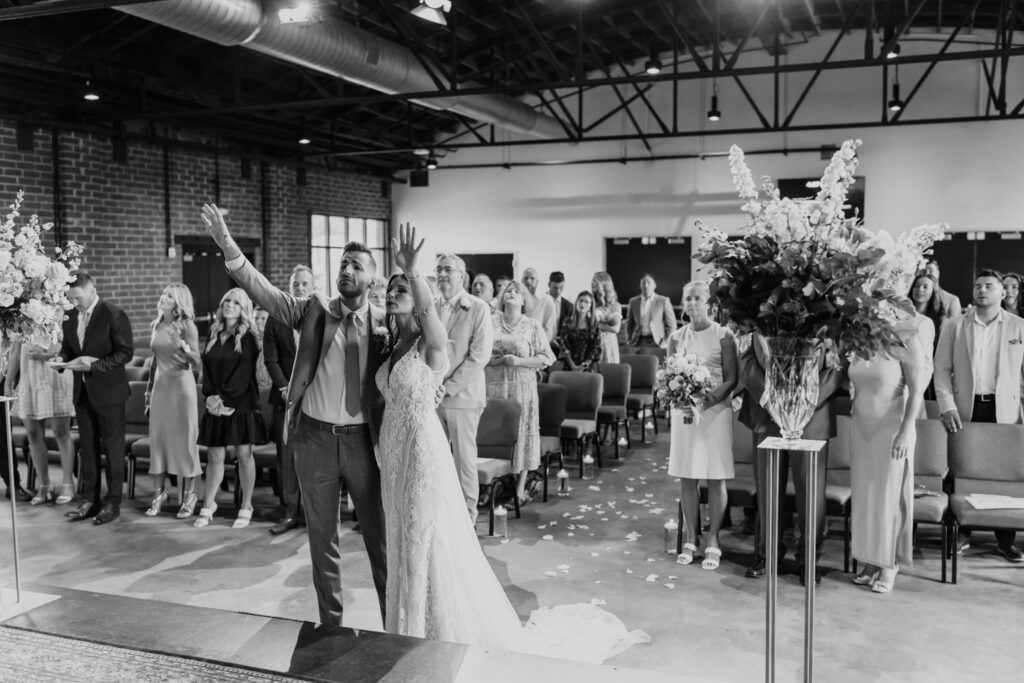 Black and white image of bride and groom praising God with hands in air photographed by Charlotte Wedding Photographer.  