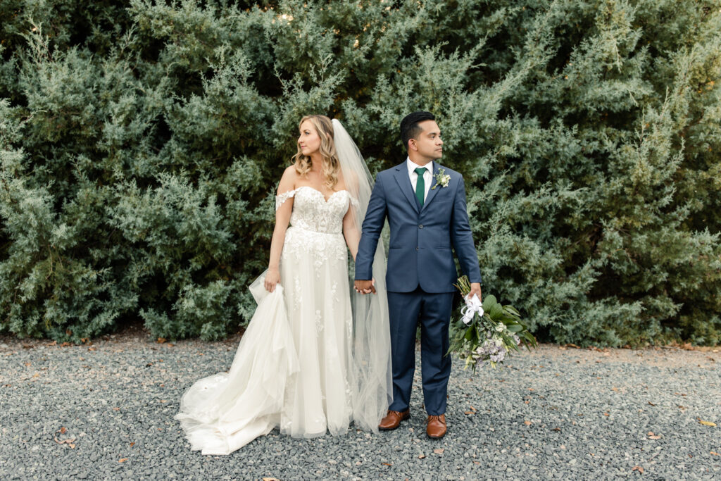 Bride with long blonde hair in a white lace dress and long veil walking holding hands with groom in blue suit at Riverwood Manor Wedding Venue. Photographed by Charlotte wedding photographer, Stephanie Bailey.