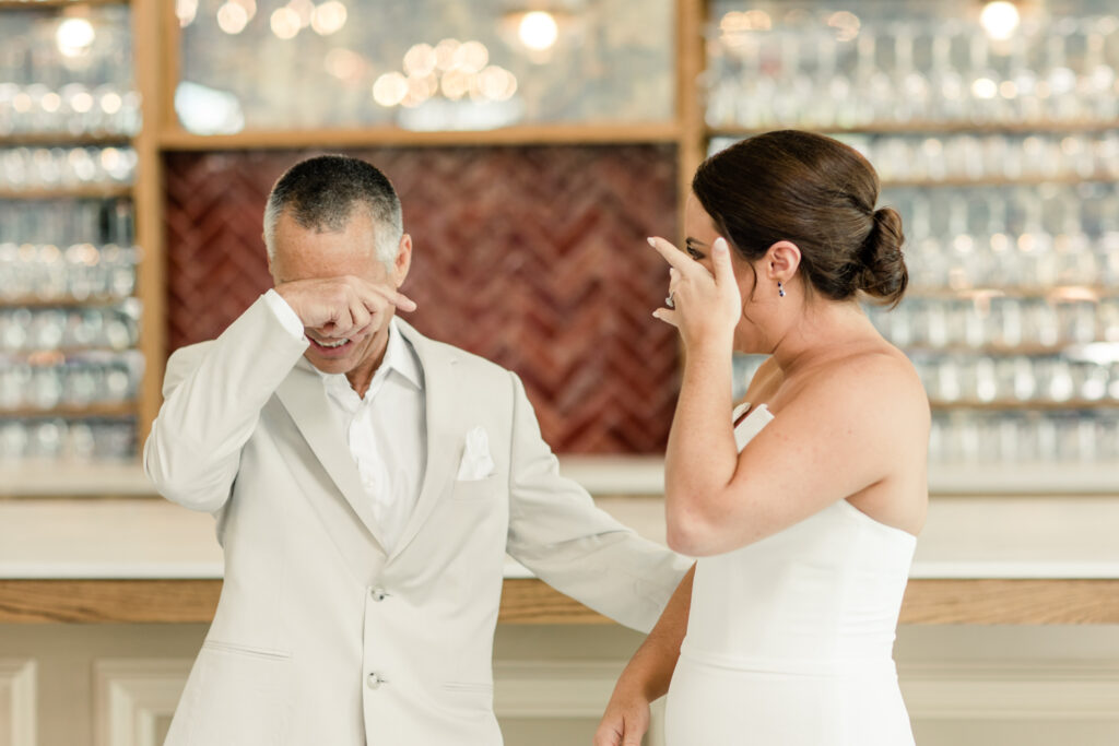 Bride, in white strapless dress, seeing her dad, in tan suit, for the first time at The Ruth wedding venue in Charlotte NC. Photographed by Charlotte Wedding Photographer.