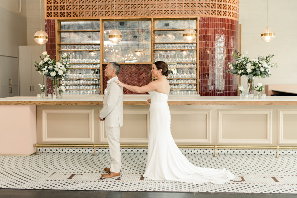 Bride, in white strapless dress, seeing her dad, in tan suit, for the first time at The Ruth wedding venue in Charlotte NC. Photographed by Charlotte Wedding Photographer.