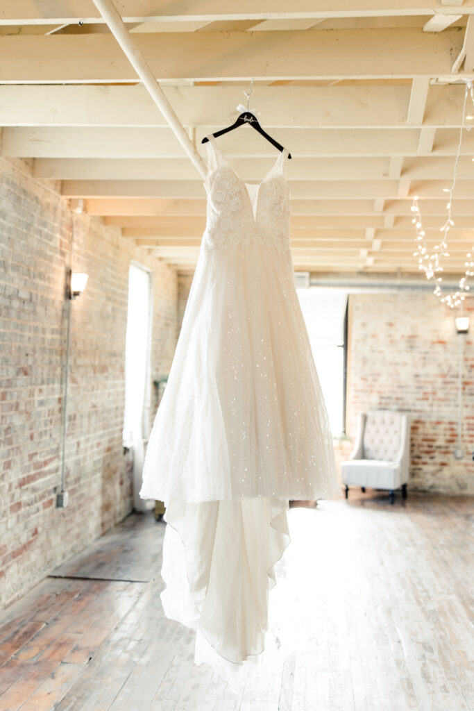 White lace dress hanging from the ceiling of at The Bottle Factory Wedding Venue. Photographed by Charlotte wedding photographer. 