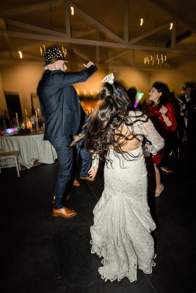 Bride with dark brown hair in a long white lace dress dancing with groom in navy suit during reception  at Fields at Skycrest Wedding Venue in Charlotte NC. Photographed by Charlotte wedding photographer.