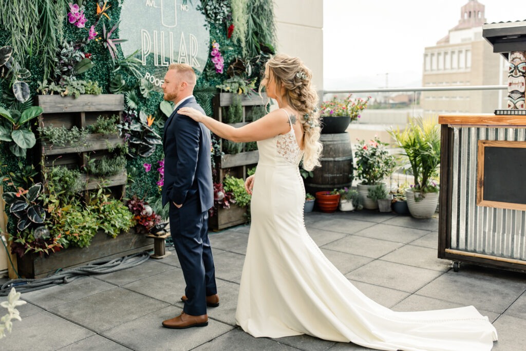 Bride in white dress doing a first look with her groom wearing a blue suit on a rooftop in Asheville NC. Photographed by Charlotte wedding photographer.